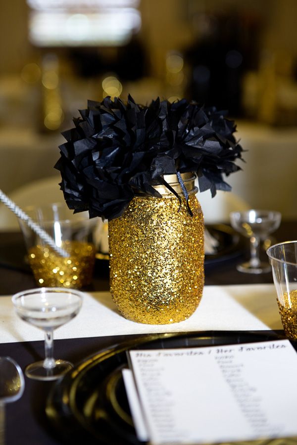 a black and gold table setting with flowers in a vase