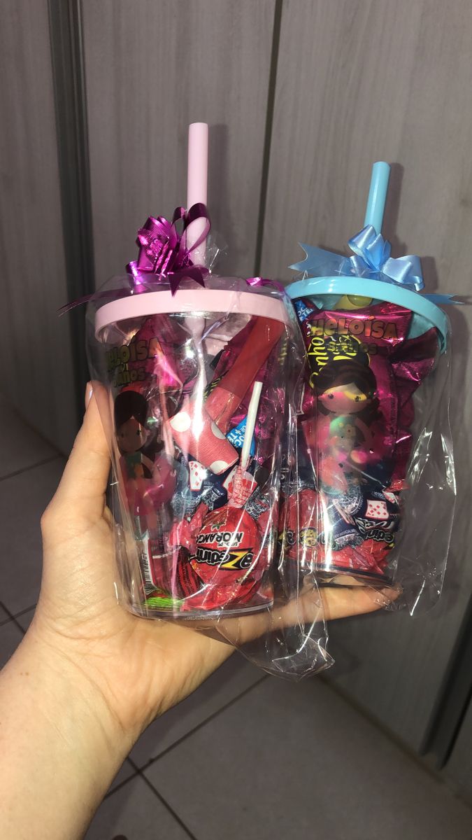 someone is holding up two plastic cups with candy in them, both wrapped in cellophane