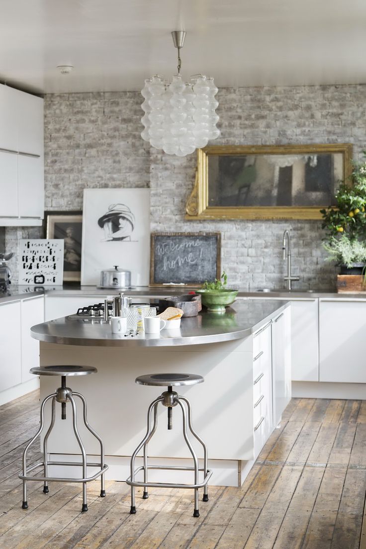 a kitchen with two stools in front of the island and an old brick wall