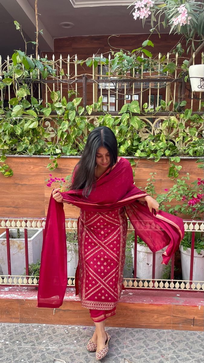 a woman in a red dress is standing on a bench