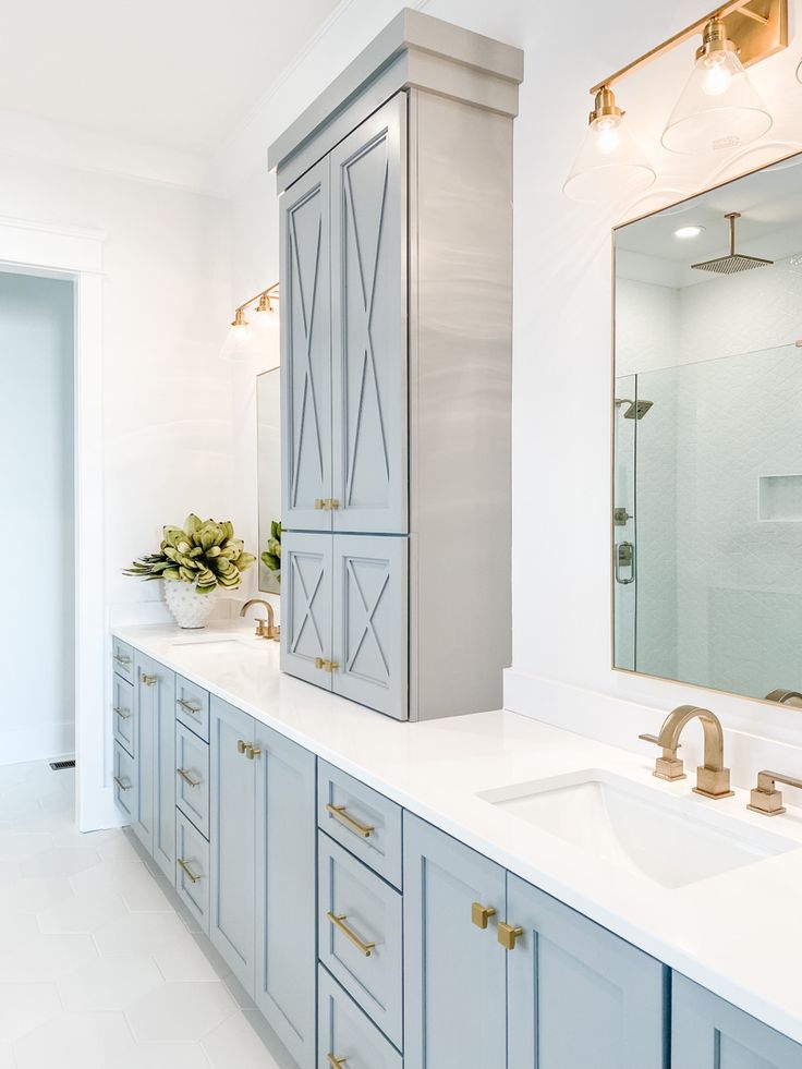 a large bathroom with two sinks and blue cabinetry in it's center area