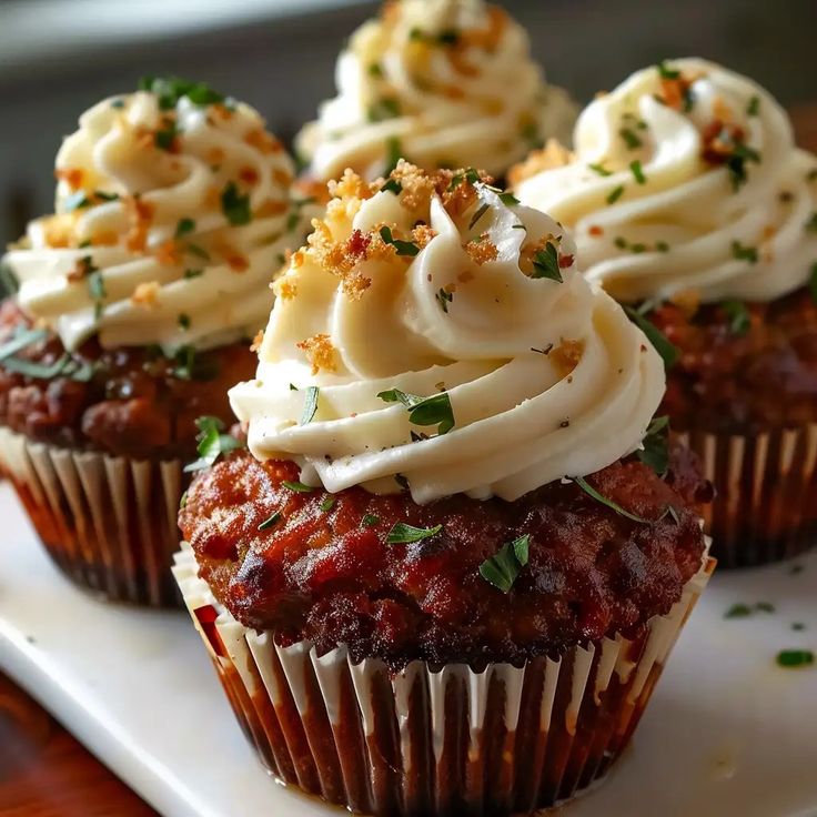 some cupcakes with white frosting and sprinkles on top are sitting on a plate