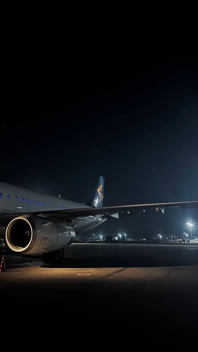 an airplane sitting on the runway at night