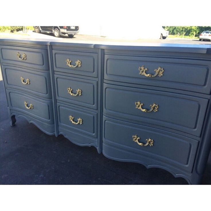 a blue dresser with gold handles and knobs on it's drawers in a parking lot