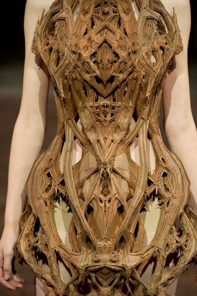 a woman is walking down the runway in a dress made out of wood