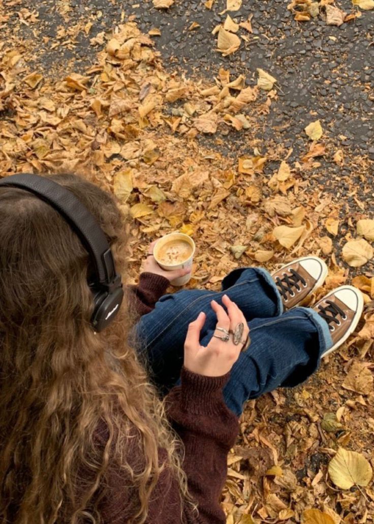 a person with headphones on sitting in leaves