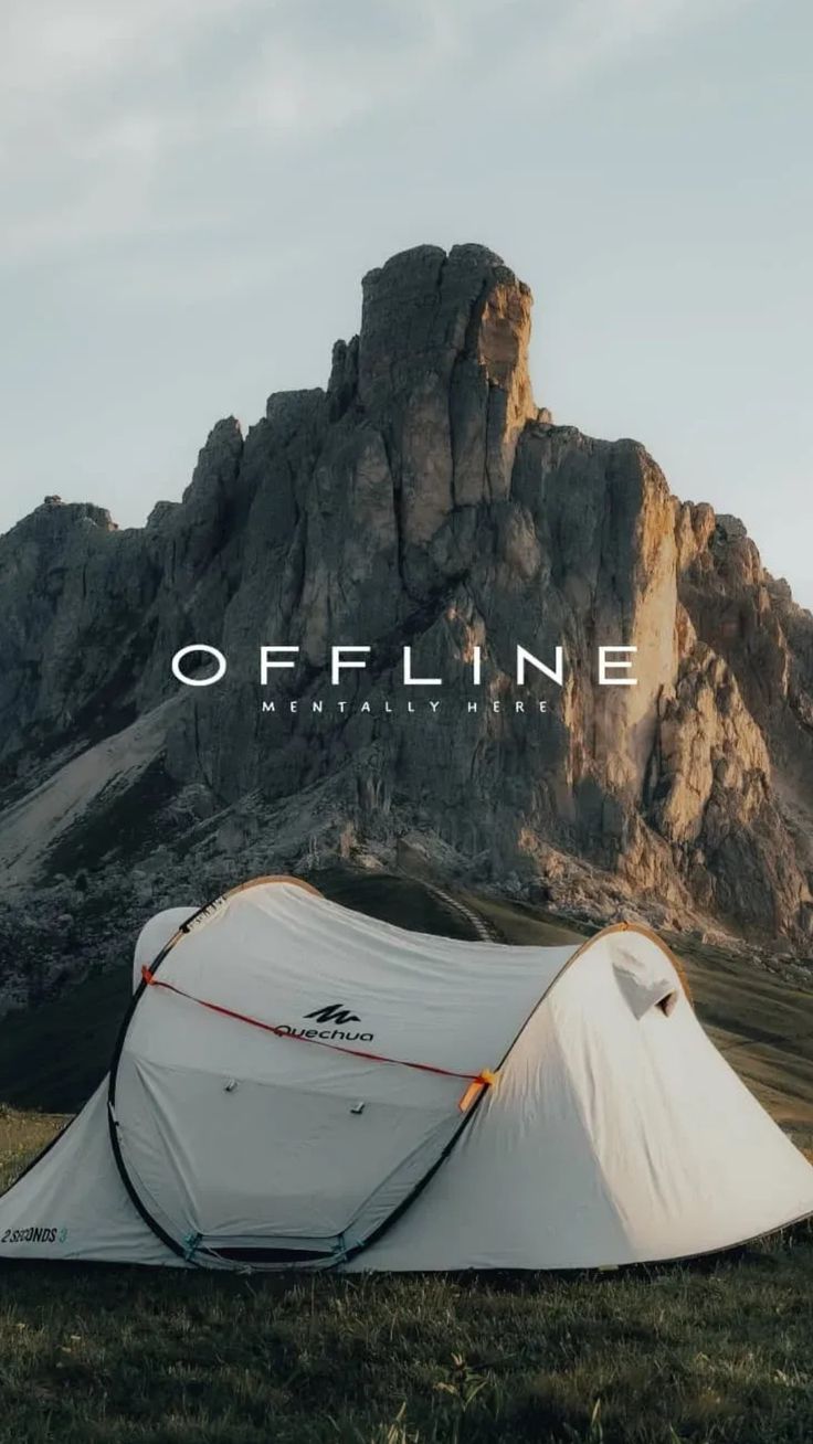 a white tent sitting on top of a lush green field next to a tall mountain