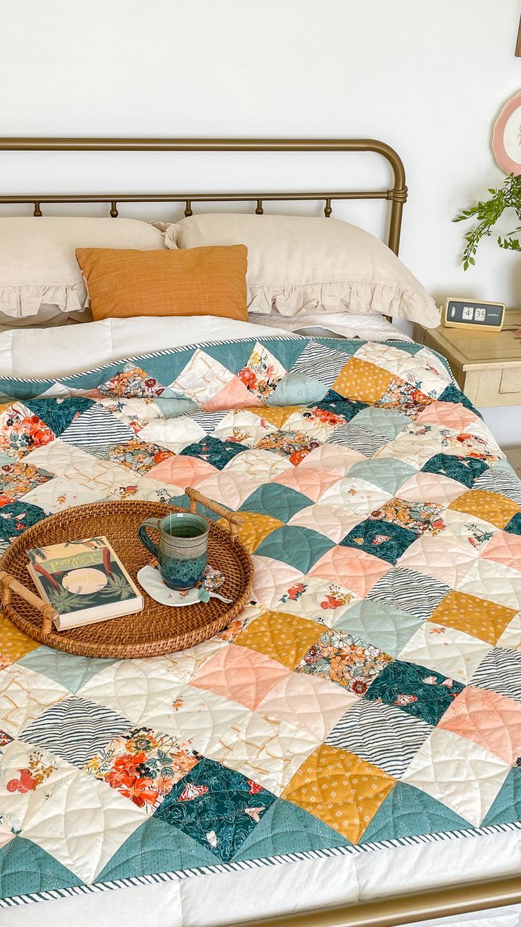 a bed topped with a quilt next to a basket filled with books on top of it