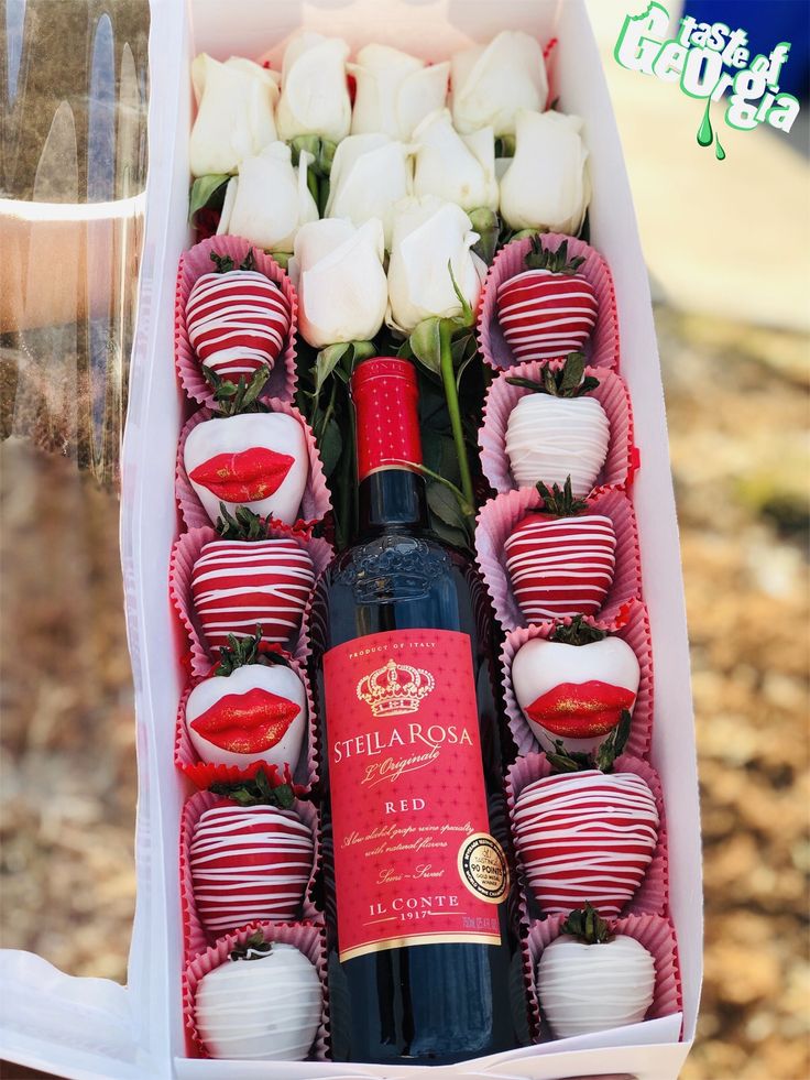 a bottle of wine and some chocolates in a box with flowers on the table