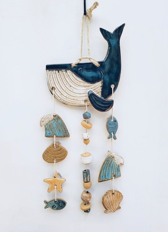 a wind chime hanging from the side of a wall with shells and sea animals on it