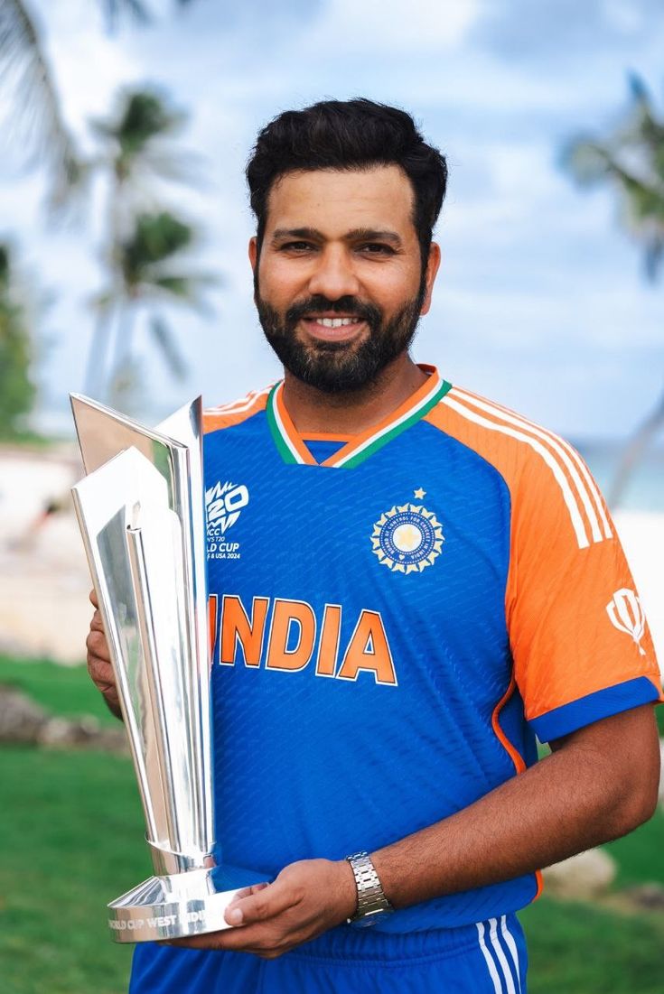 a man holding a silver trophy in his right hand and smiling at the camera with palm trees in the background