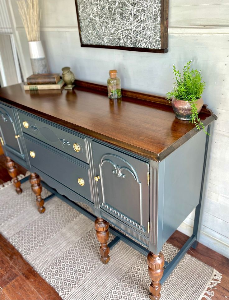 an old dresser is painted blue and has gold hardware on the drawers, along with a potted plant