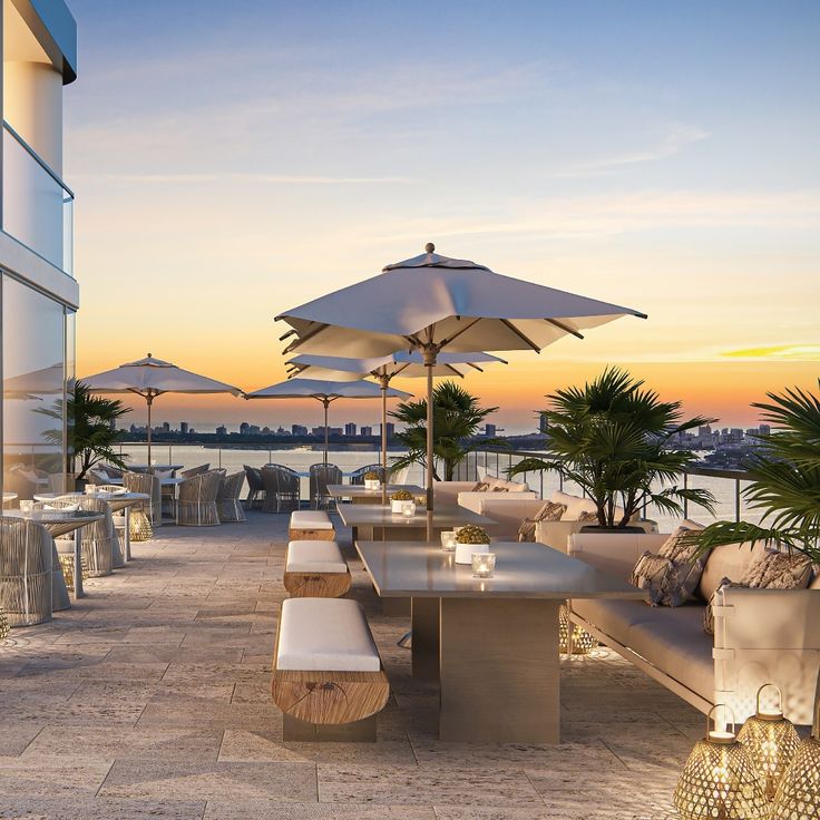 an outdoor dining area with tables and umbrellas on the deck at sunset or dawn