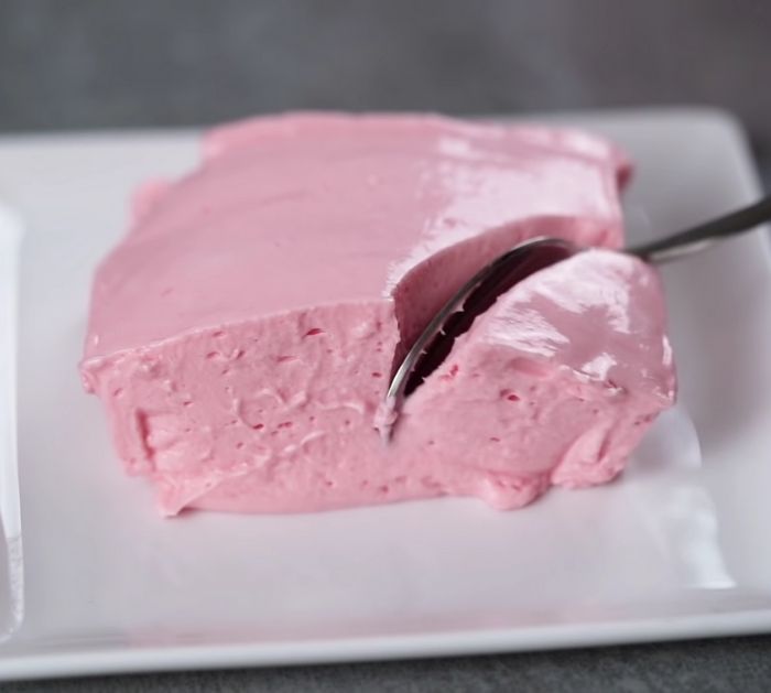 a piece of pink cake on a white plate with a spoon in it and two forks sticking out of the top