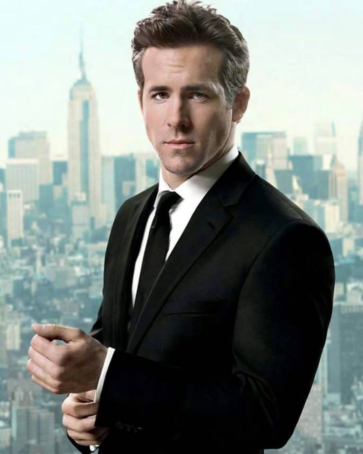 a man in a suit and tie posing for a picture with a cityscape behind him