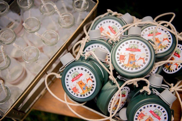 some green and white bottles are sitting in a box with wine glasses around it on the table