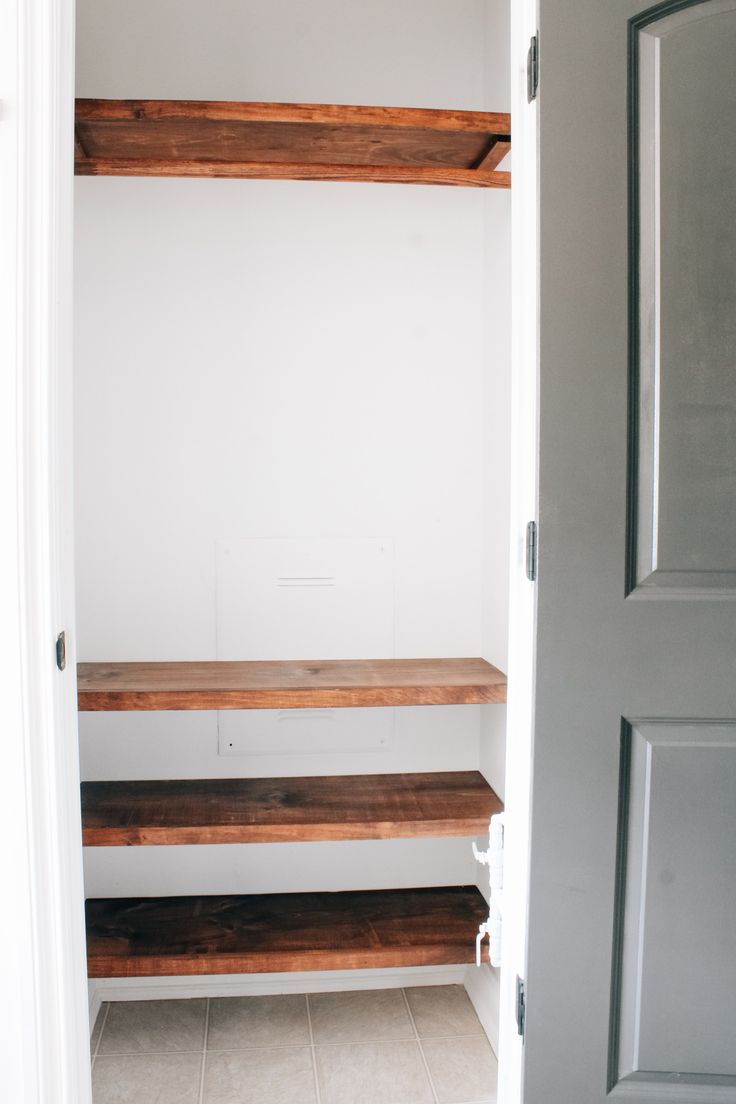 an empty closet with wooden shelves and white walls