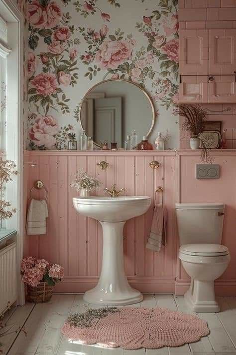 a bathroom with pink walls and floral wallpaper on the walls, along with a white pedestal sink and toilet