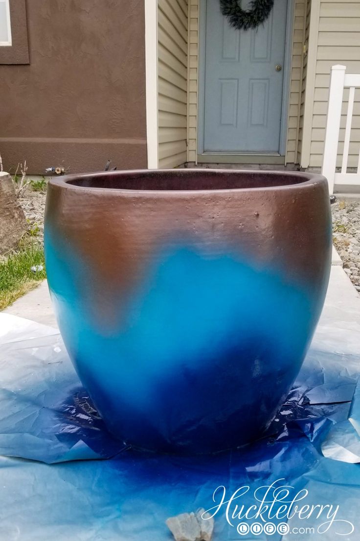 a large pot sitting on top of a blue tarp in front of a house