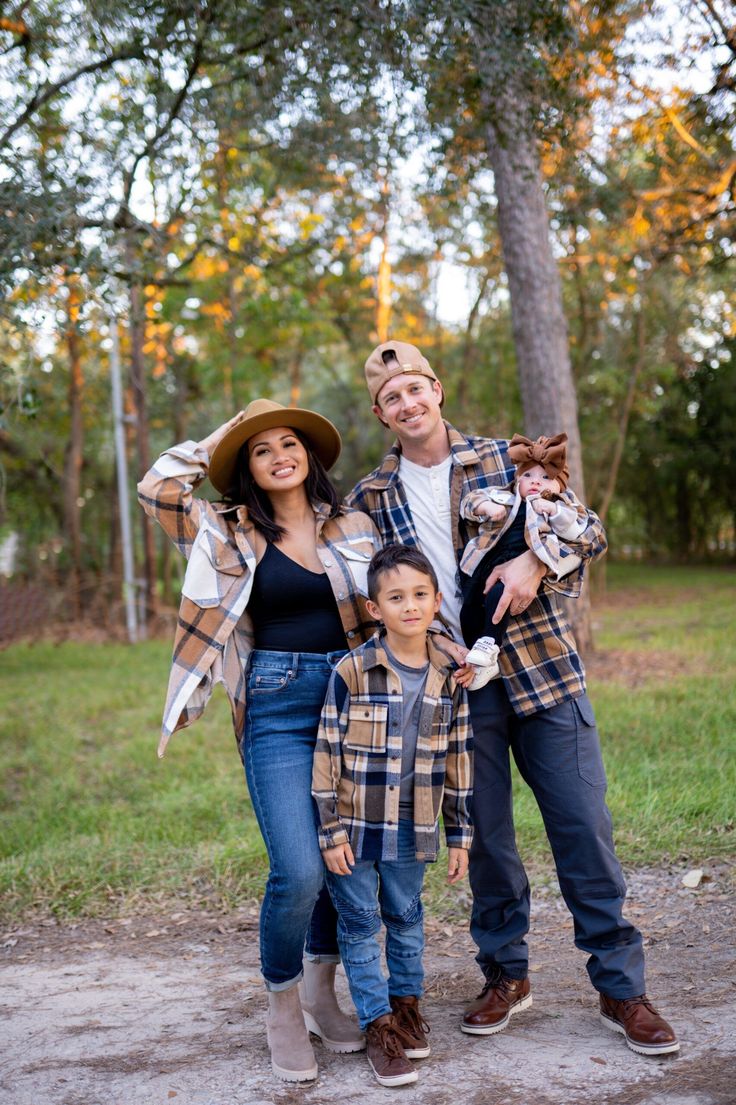 a man, woman and child posing for a photo in front of some trees with their arms around each other