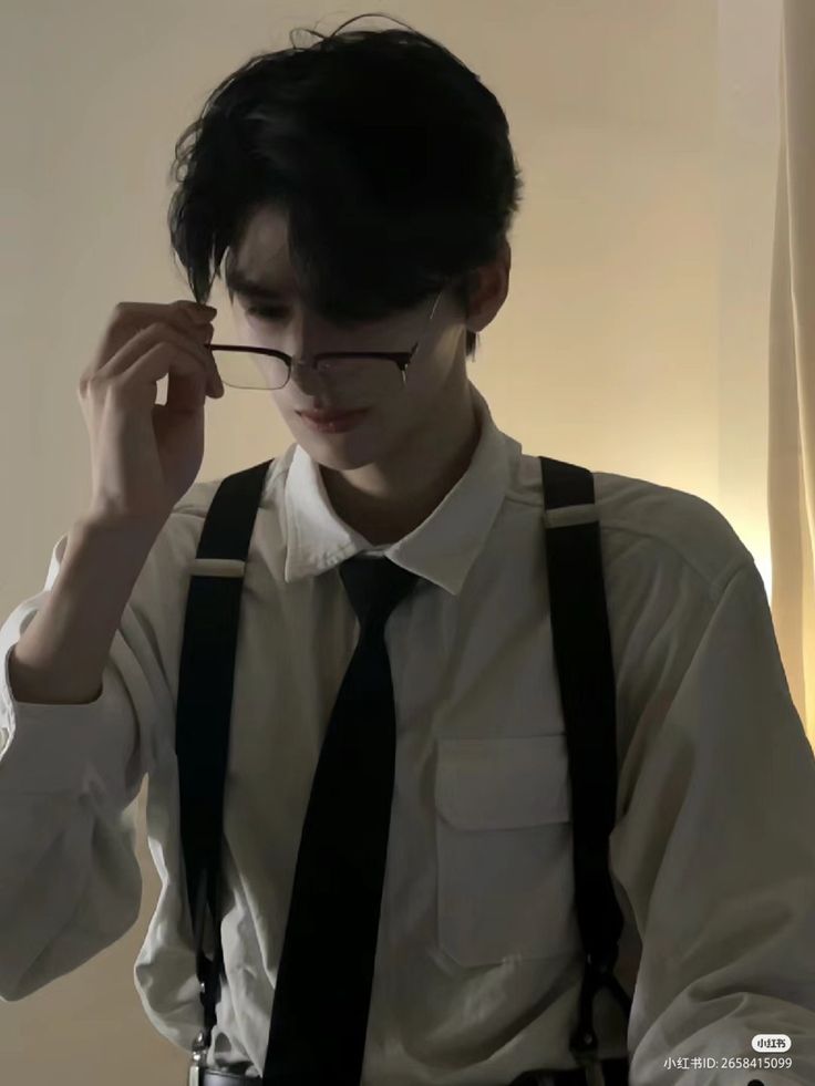 a young man wearing suspenders and glasses