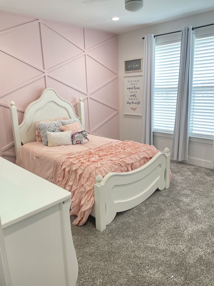 a bedroom with pink walls and white furniture