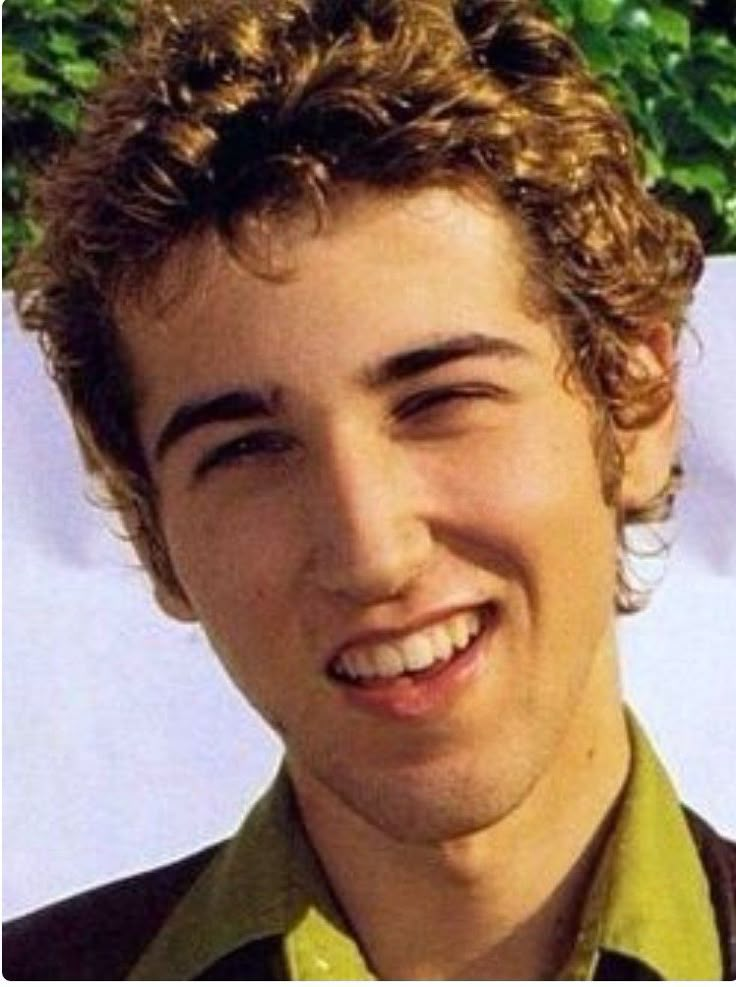 a young man with curly hair smiling at the camera