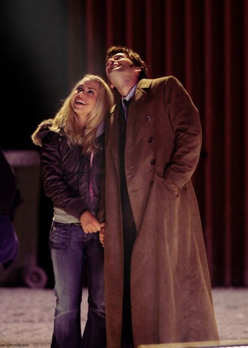 a man and woman standing next to each other in front of a red stage curtain