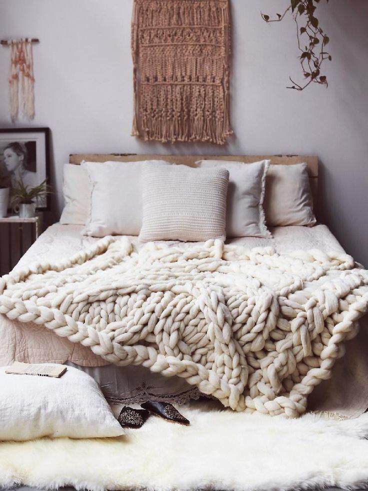 a bed with blankets and pillows on top of it in a bedroom next to a wall hanging