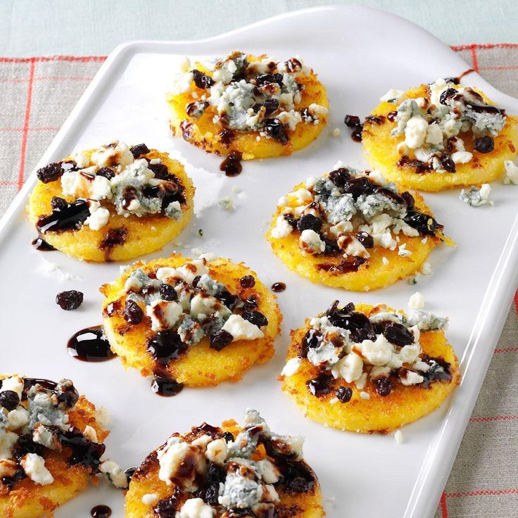 small pastries with blue cheese and olives on a white tray