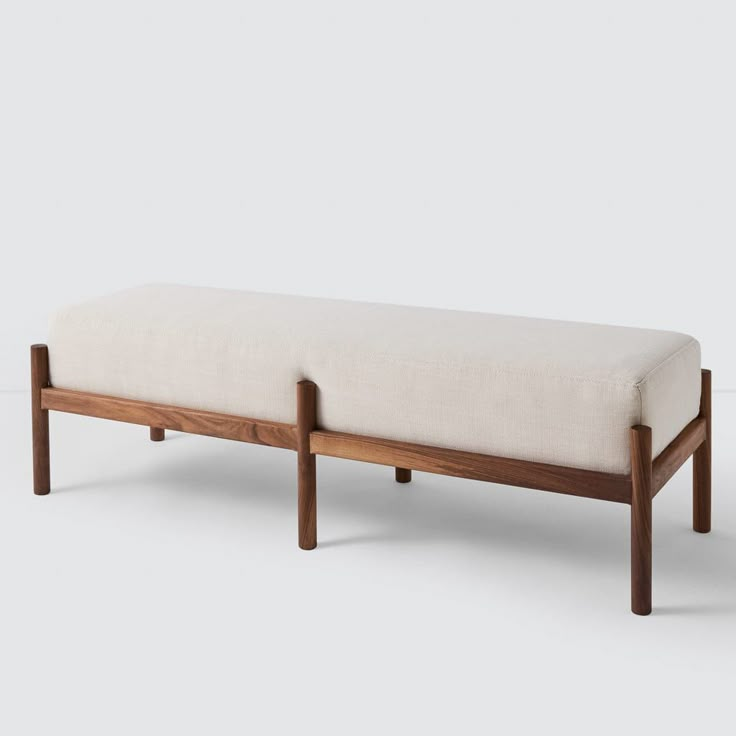 a wooden bench with a white upholstered seat and back rest on an off - white background