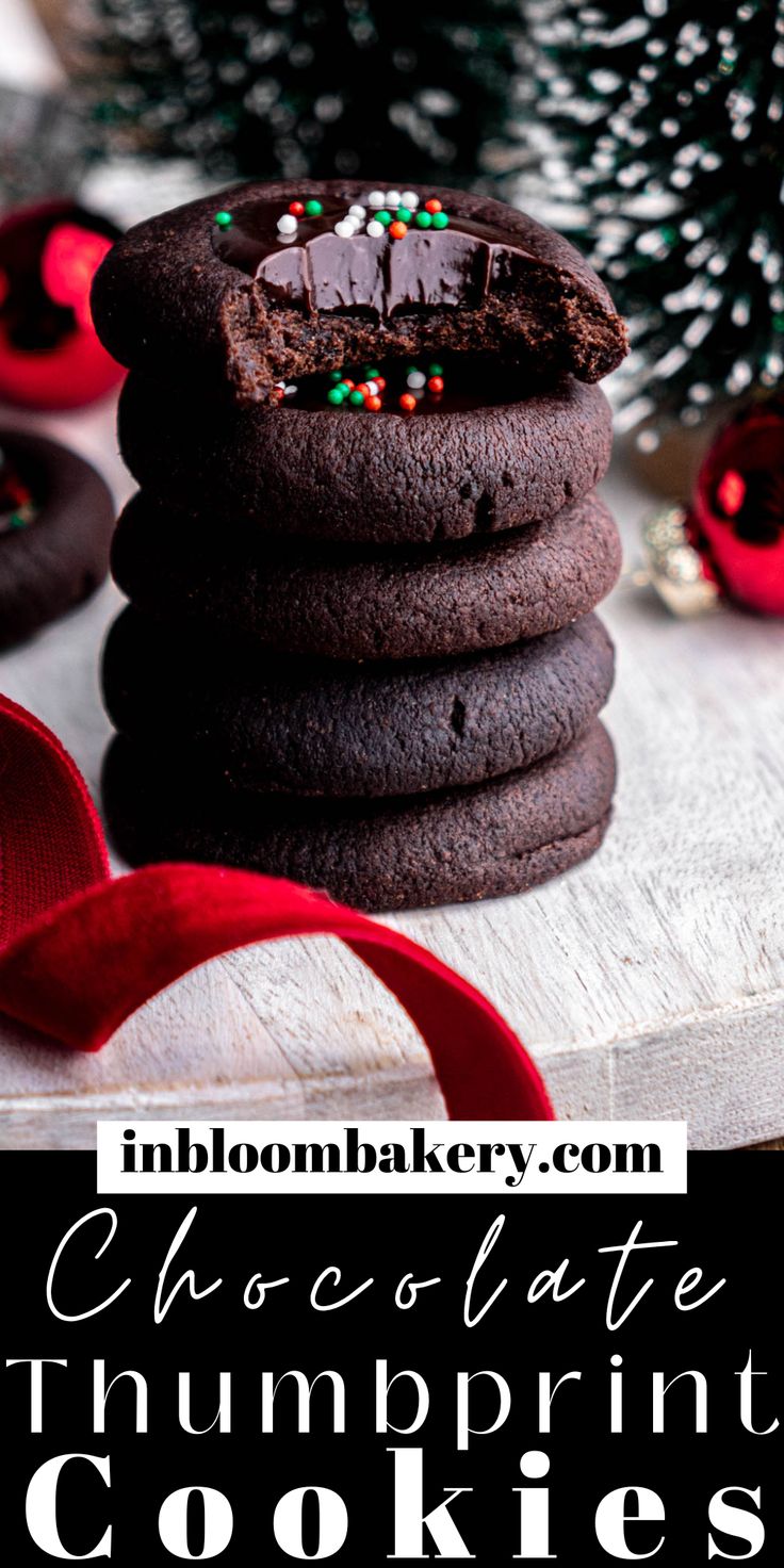 chocolate thumbprint cookies stacked on top of each other next to a christmas tree and red ribbon