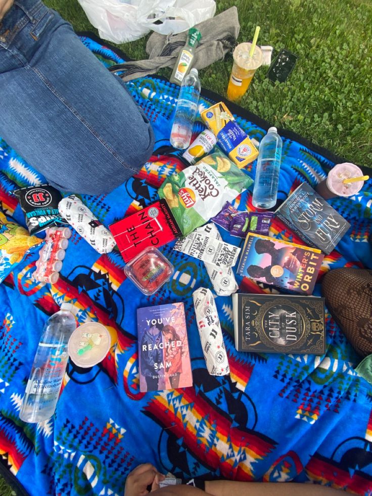 a person laying on top of a blue blanket covered in bottles and other items next to each other