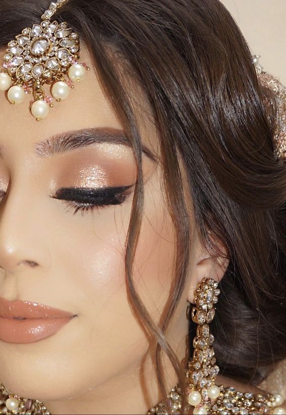 a close up of a woman with makeup and accessories on her head, wearing a bridal outfit