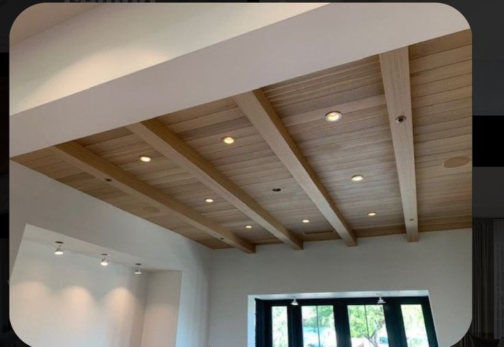 an empty room with wooden ceiling and windows