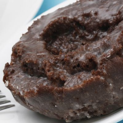 a chocolate doughnut on a plate with a fork