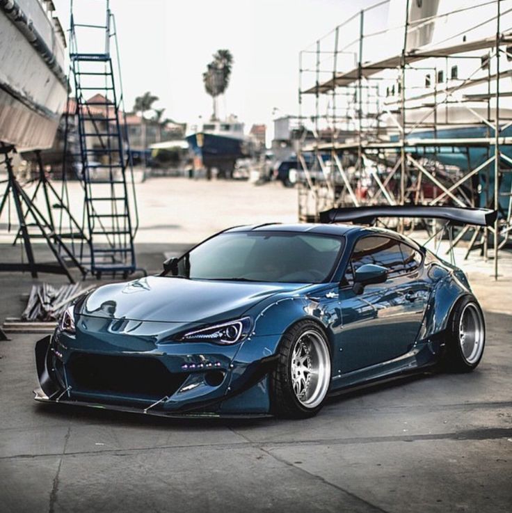 a blue sports car parked in front of some scaffolding