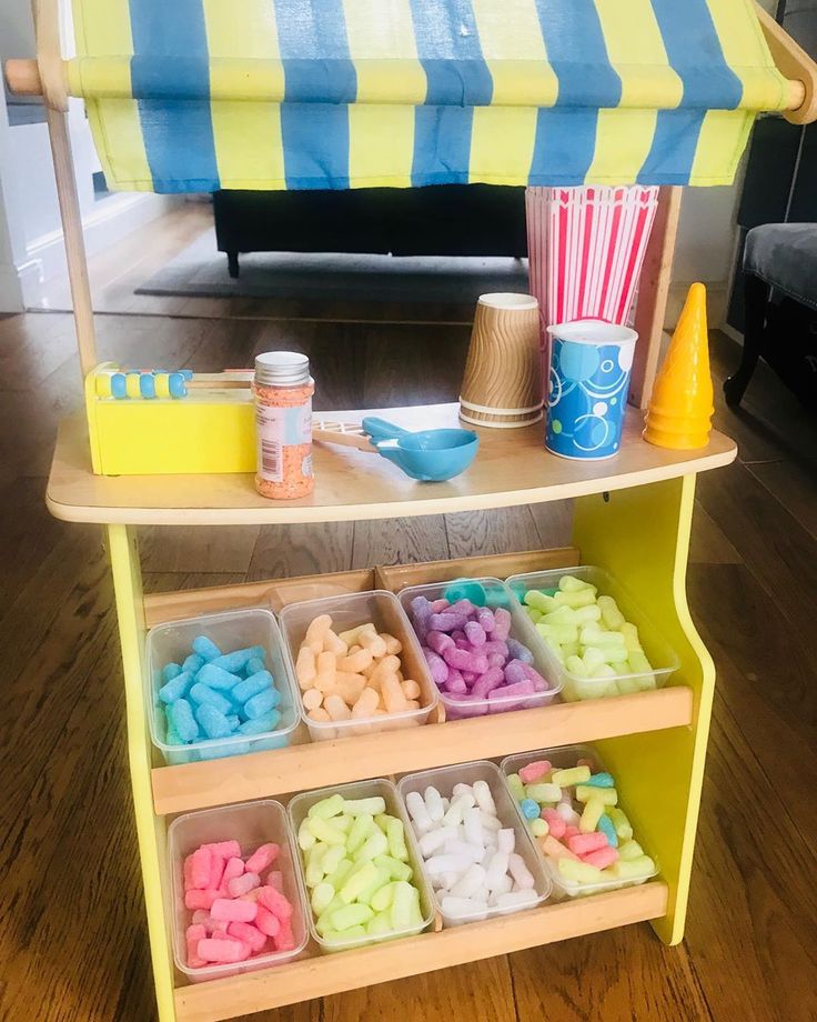 an ice cream stand is filled with different colored candies and cups on the table