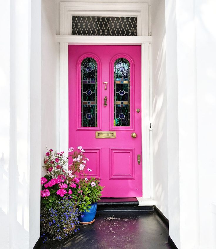 a pink front door with two potted flowers