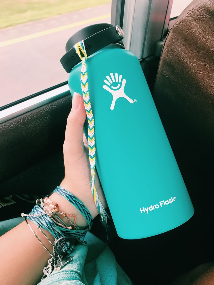 a person holding onto a hydro flask while sitting in a car