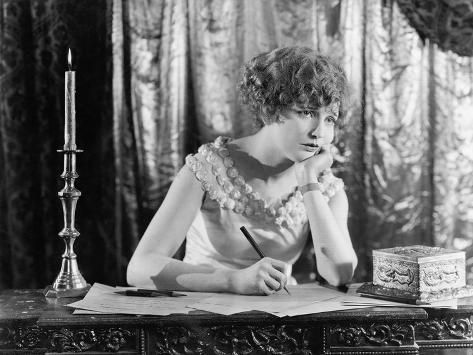 a woman sitting at a desk with a pen in her hand