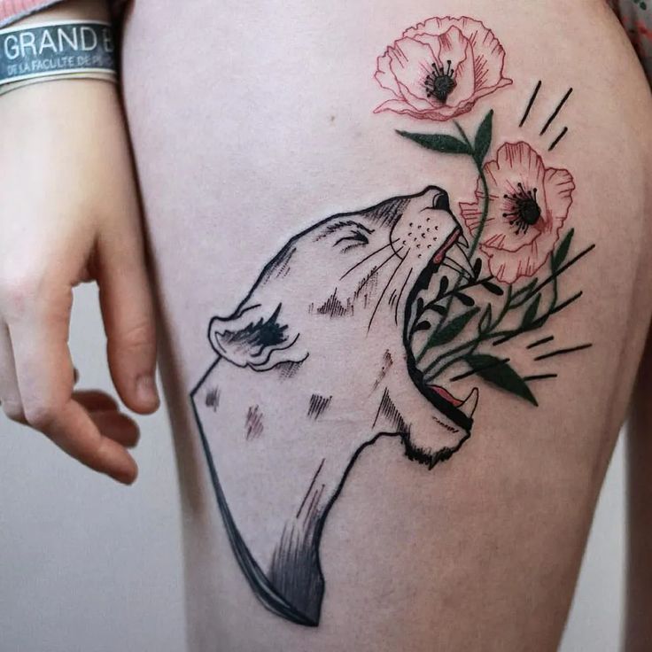 a woman's thigh with a tattoo of a wolf and flowers