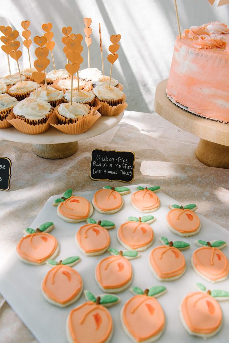 a table topped with lots of cupcakes covered in frosting and orange icing