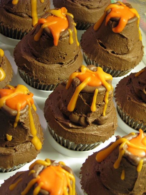 chocolate cupcakes with orange and yellow icing sitting on top of each other