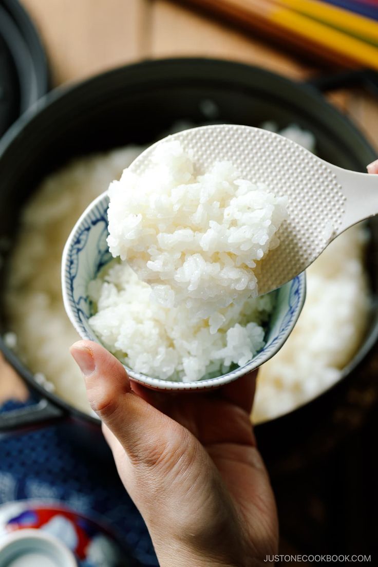 a person holding a spoon with rice in it