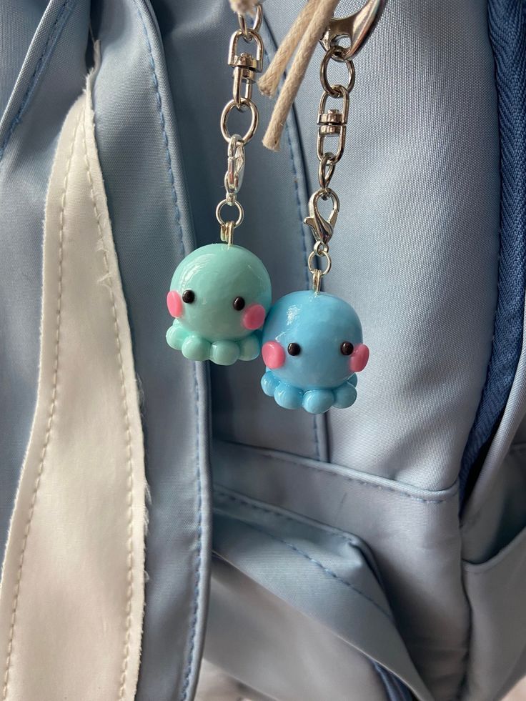 two little blue and pink octopus keychains hanging from a bag