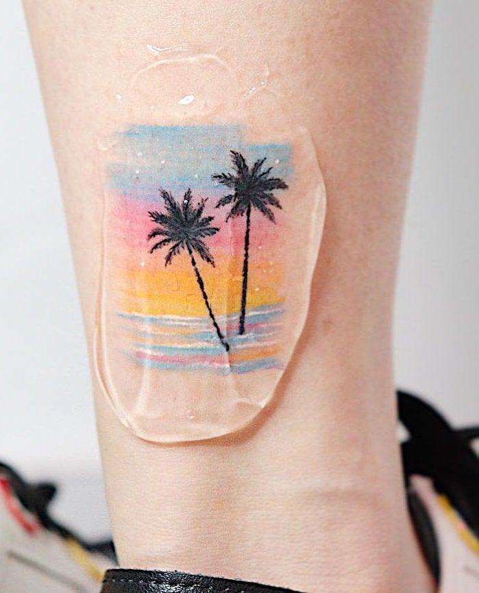 a woman's leg with a palm tree tattoo on it