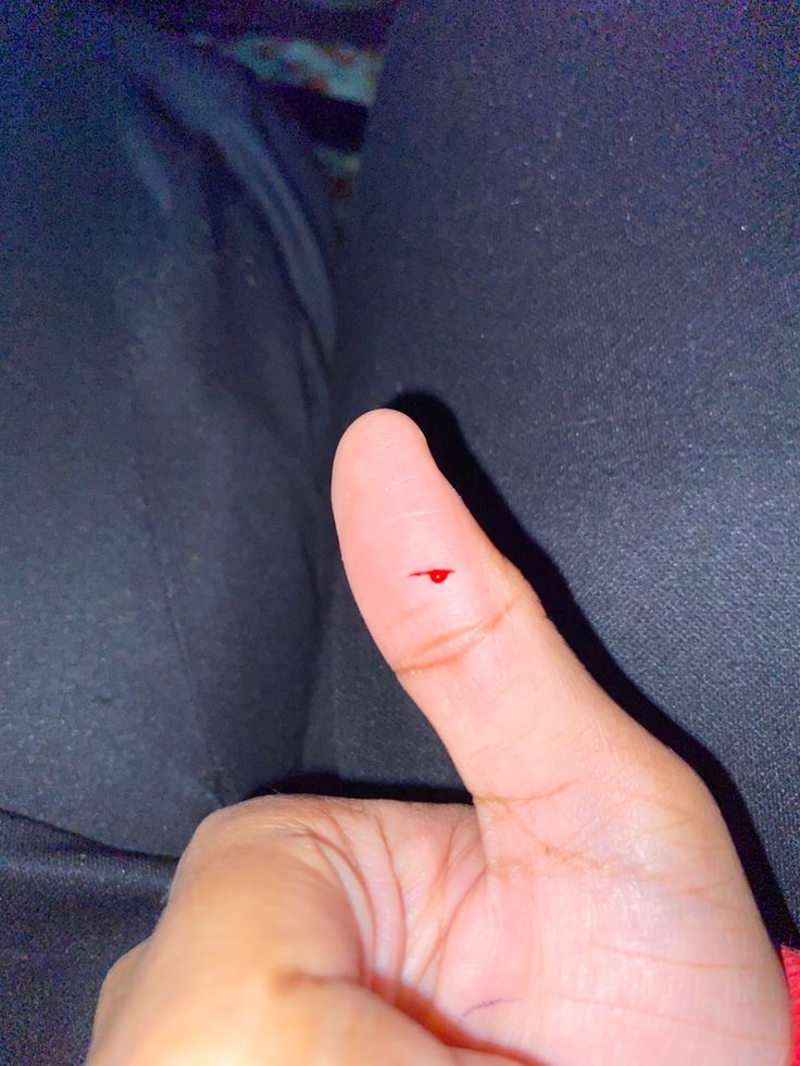 a person's finger with a red dot in the middle of their thumb, pointing to the left