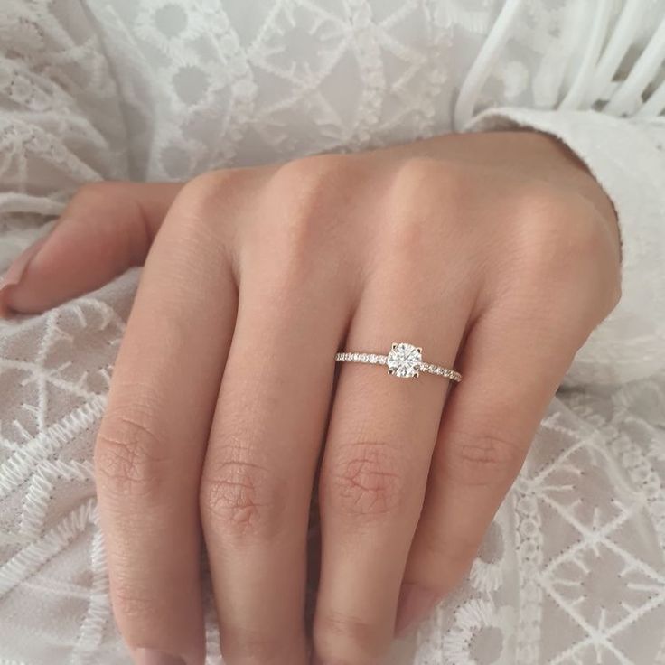 a close up of a person's hand with a diamond ring on their finger