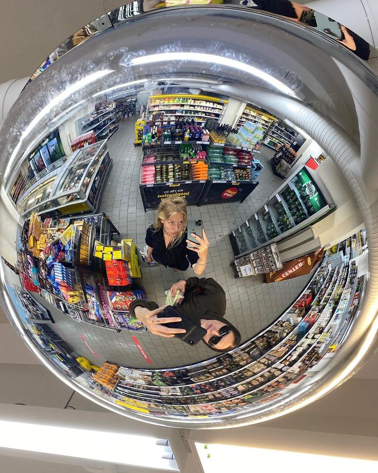 a woman taking a selfie in the middle of a shopping mall's circular mirror